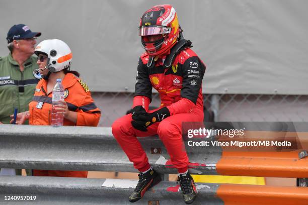 Carlos Sainz Jr of Ferrari and Spain sits on the guard rail after crashing into Sergio Perez of Red Bull and Mexico during qualifying ahead of the F1...