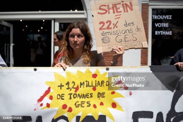 Young woman holds a cardboard reading 'SHEIN = 22% of warming gas emitted for youths. 1.2Gt of warming gas'. Members of XR Toulouse organized a...