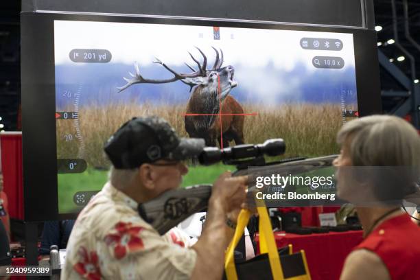 An attendee looks through a rifle scope at the ATN Corp. Booth during the National Rifle Association annual convention in Houston, Texas, US, on...