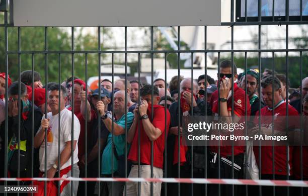 Liverpool fans cover their mouths and noses as they queue to gain entry to the stadium as Kick off is delayed ahead of the UEFA Champions League...