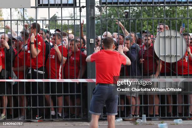 Liverpool supporters look through the closed gates of the Stade de France, some feeling the effects of tear gas before the UEFA Champions League...