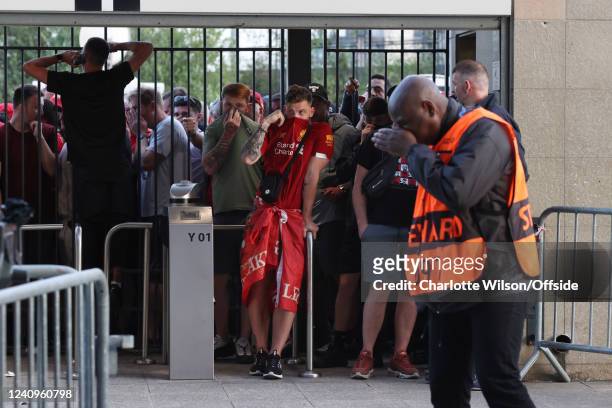 Liverpool supporters look through the closed gates of the Stade de France, some feeling the effects of tear gas before the UEFA Champions League...