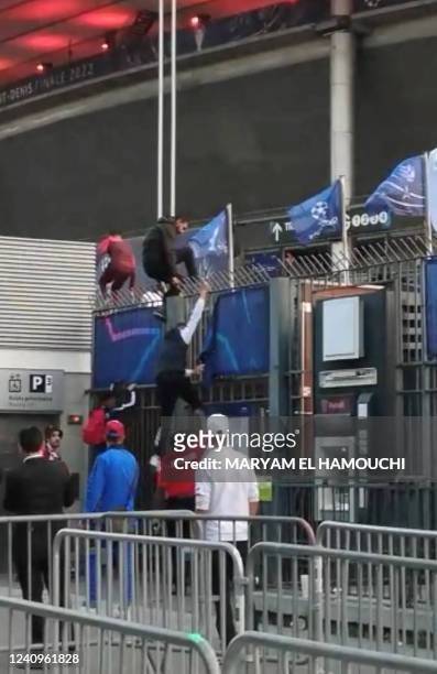 This grab taken from an AFP video shows fans climbing the fence of the Stade de France before the UEFA Champions League final football match between...