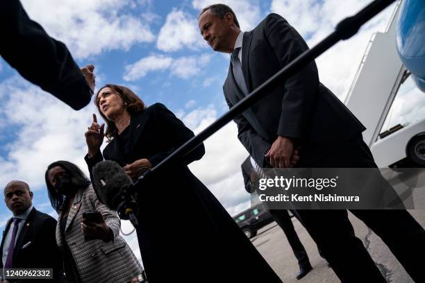 Vice President Kamala Harris speaks to the traveling press pool as Second Gentleman Doug Emhoff looks on, under the wing of Air Force 2...