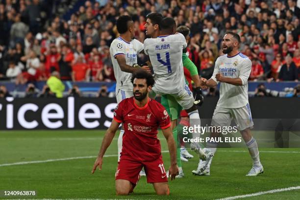 Real Madrid's teammates congratulate Real Madrid's Belgian goalkeeper Thibaut Courtois after he saved a shot by Liverpool's Egyptian midfielder...
