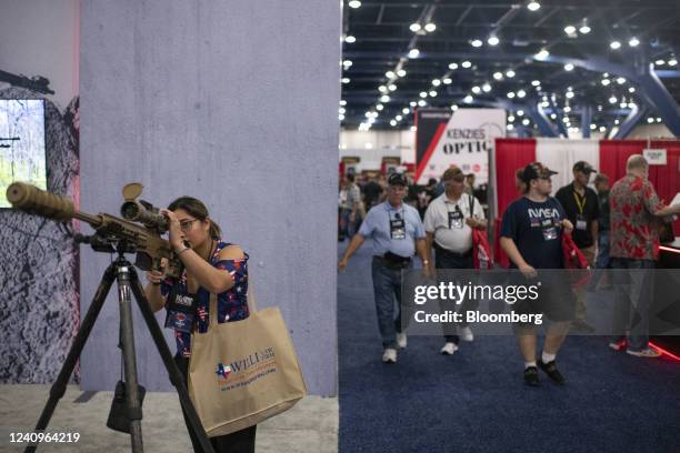 An attendee looks through the scope of a Barrett Mk22 MOD 0 rifle at the company's booth during the National Rifle Association annual convention in...