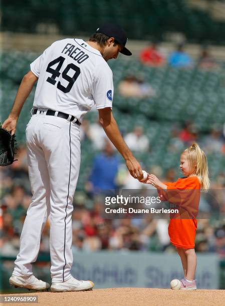 Starting pitcher Alex Faedo of the Detroit Tigers presents a baseball to a young girl before the start of a game against the Cleveland Guardians at...