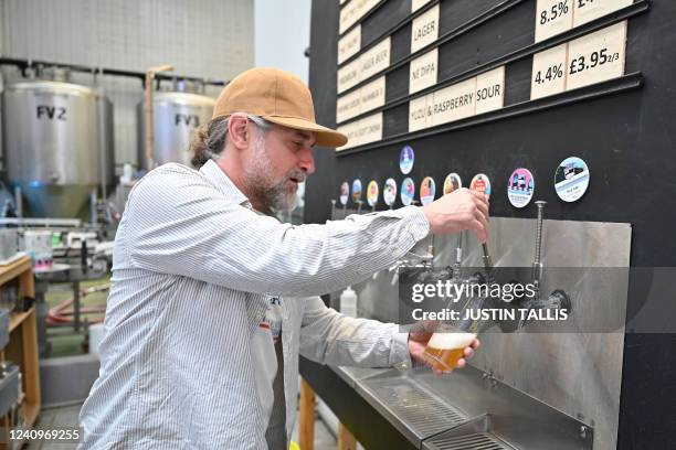 Worker pours a pint of beer at Pressure Drop Brewery, in north London, on May 21, 2022. Members of staff at the Pressure Drop brewery are taking part...