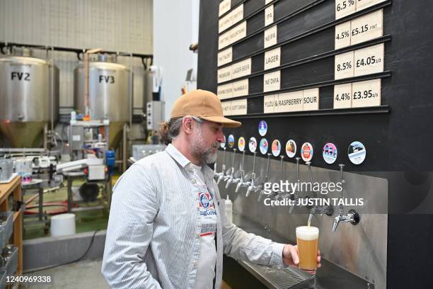 Worker pours a pint of beer at Pressure Drop Brewery, in north London, on May 21, 2022. Members of staff at the Pressure Drop brewery are taking part...