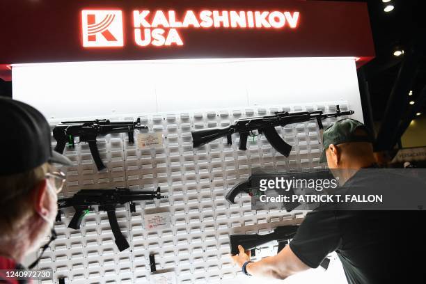 Attendees hold American made AK-47 style 7.62mm semi-automatic rifles from Kalashnikov USA during the National Rifle Association Annual Meeting at...