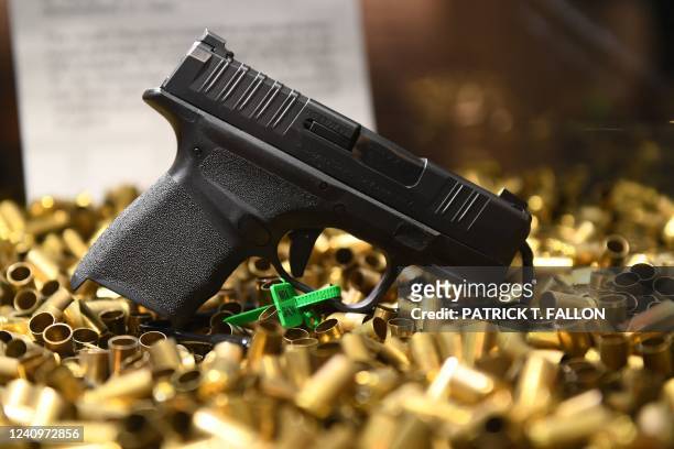 Springfield Armory Hellcat 9mm micro-sized pistol that has fired 20,000 rounds is displayed with ammunition shell casings during the National Rifle...