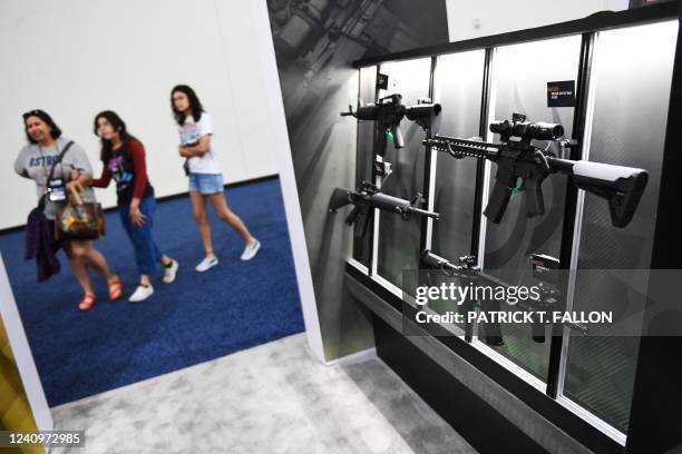 Attendees walk past a display of Stag Arms AR-15 style semi-automatic rifles during the National Rifle Association Annual Meeting at the George R....