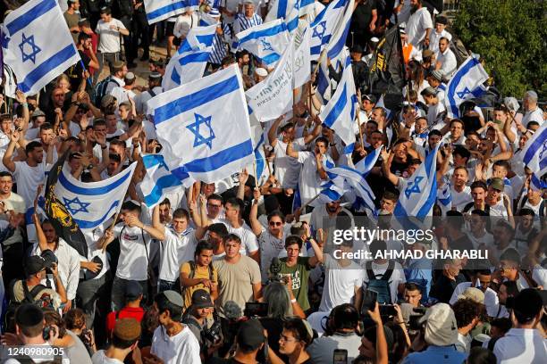 Demonstrators march with Israeli flags during the Israeli 'flags march' to mark "Jerusalem Day outside the old city's Damascus Gate on May 29, 2022....