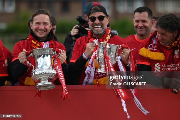 Liverpool's assistant manager Pepikn Lijnders holds the FA cup Trophy and Liverpool's German manager Jurgen Klopp holds the League cup Trophy as they...