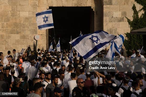 Israeli Jewish citizens dance and hold Israeli flags as they take part at the annual Flag March by Damascus Gate on May 29, 2022 in Jerusalem,...