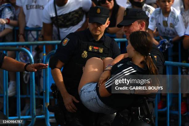 Members of Spanish National Police forces evacuate a woman as Real Madrid fans gather at the Cibeles square to celebrate their team's 14th European...