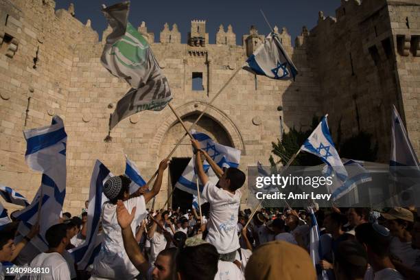 Israeli Jewish citizens dance and hold Israeli flags as they take part at the annual Flag March by Damascus Gate on May 29, 2022 in Jerusalem,...