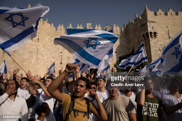 Israeli Jewish citizens dance and hold Israeli flags as they take part at the annual Flag March by Damascus Gate on May 29, 2022 in Jerusalem,...