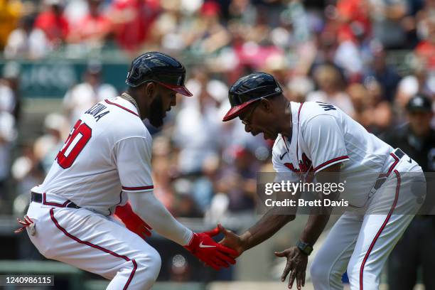 Marcell Ozuna of the Atlanta Braves celebrates his solo home run with third-base coach Ron Washington against the Miami Marlins in the first inning...