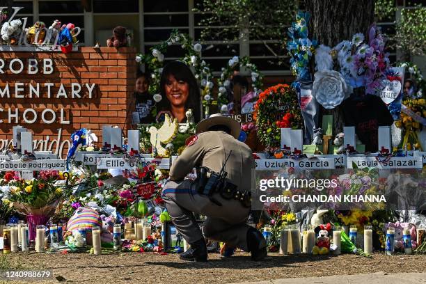 Police officer clears the makeshift memorial before the visit of US President Joe Biden at Robb Elementary School in Uvalde, Texas, on May 29, 2022....