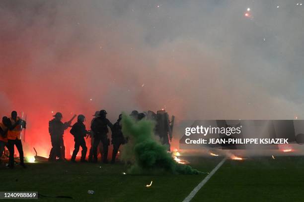 Riot police officers clash with Saint-Etienne's fans who invaded the pitch after being defeated by Auxerre at the end of the French L1-L2 play-off...