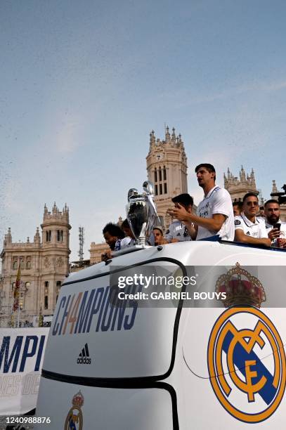 Real Madrid's Belgian goalkeeper Thibaut Courtois and teammates celebrate with their trophy as they wave from an open-top bus at the Cibeles square...