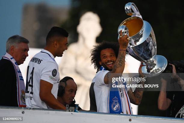 Real Madrid's Brazilian defender Marcelo holds their trophy next to Real Madrid's Italian coach Carlo Ancelotti and Real Madrid's Brazilian...