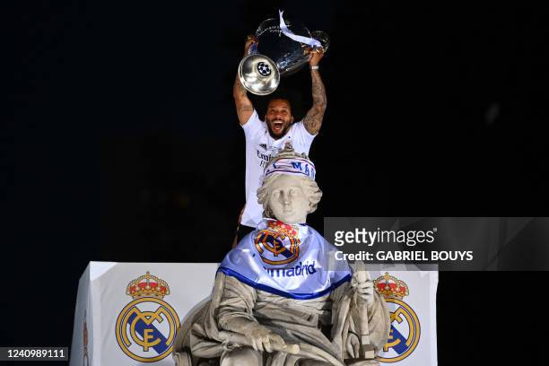 Real Madrid's Brazilian defender Marcelo lifts their trophy ontop of the statue of Greek goddess Cybele on May 29, 2022 at the Cibeles square in...