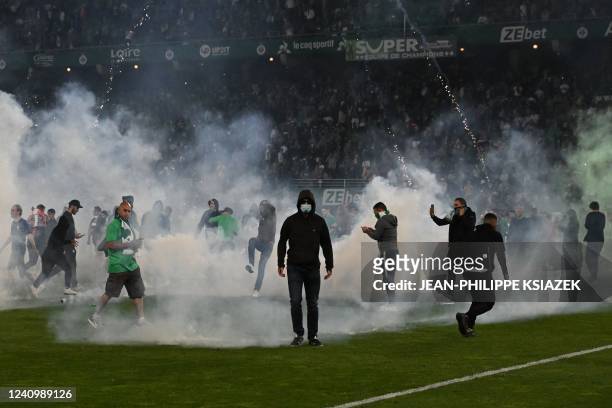 Saint-Etienne's fans invade the pitch through smoke after being defeated at the end of the French L1-L2 play-off second leg football match between AS...