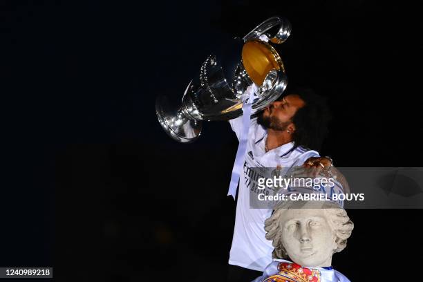 Real Madrid's Brazilian defender Marcelo kisses their trophy ontop of the statue of Greek goddess Cybele on May 29, 2022 at the Cibeles square in...