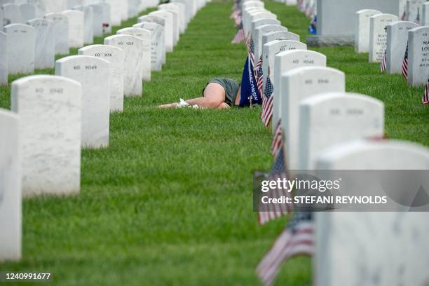 Woman lies in front of a grave in Section 60 at Arlington Cemetery in Arlington, Virginia, on May 29, 2022.