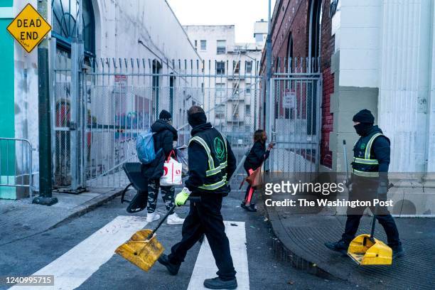 Early in the morning a homeless man and woman quickly pick up their belongings as Urban Alchemy crews begin their daily cleaning of the streets in...