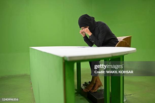 In this photograph taken on May 28 an Afghan female presenter with news network 1TV, Lima Spesaly with her face covered by a veil, takes a break...
