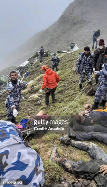 Armed Police Force, Rescue team carry the bodies of the passengers from the crash site of Tara Air at the hilly area of Thasang village of Mustang...