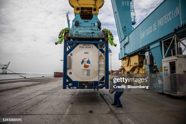 Gantry crane lifts a chemical tank onto a container vessel at the Muelle Sur terminal, operated by APM Terminals, at the Port of Barcelona in...