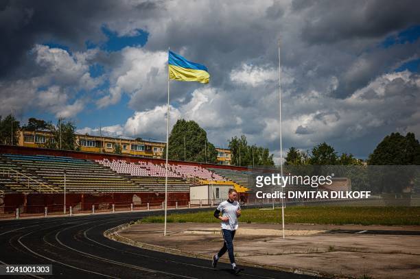 Photograph shows a man jogging at a stadium in the centre of the town of Slavutych on May 28 amid the Russian invasion of Ukraine. - More than a 100...