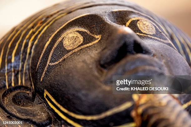 This picture taken on May 30, 2022 shows the face on one of the sarcophaguses found in a cache dating to the Egyptian Late Period after its discovery...