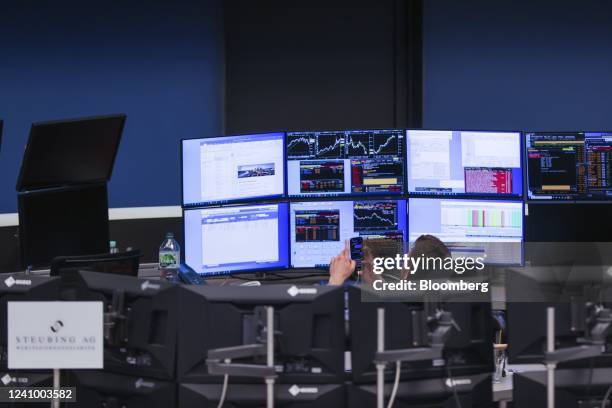 Trader uses his mobile phone while monitoring financial data near empty desks on the trading floor trading floor of the Frankfurt Stock Exchange,...