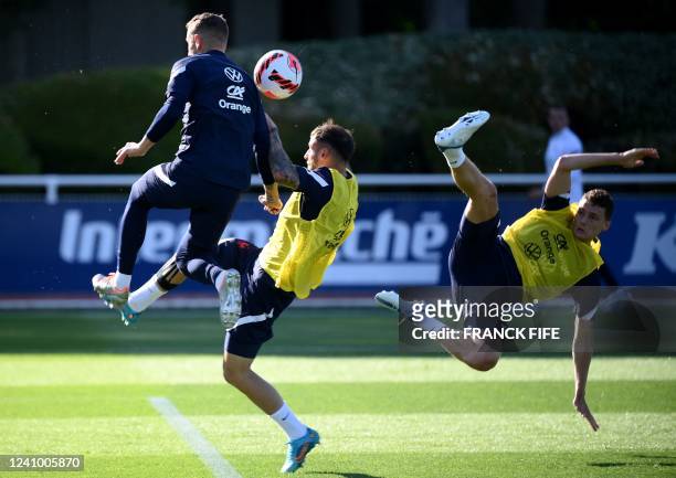 France's defender Luca Digne kicks the ball next to France's defender Jonathan Clauss and France's defender Bejamin Pavard during a training session...