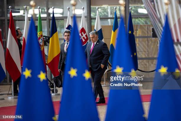 Viktor Orban Prime Minister of Hungary arrives at the special EU summit, walking next to the European flags behind the flag of Europe and talks to...