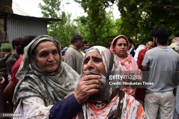 People weep outside a house that was damaged in an encounter where two militants were neutralized, at Gundipora village on May 30, 2022 in Pulwama,...