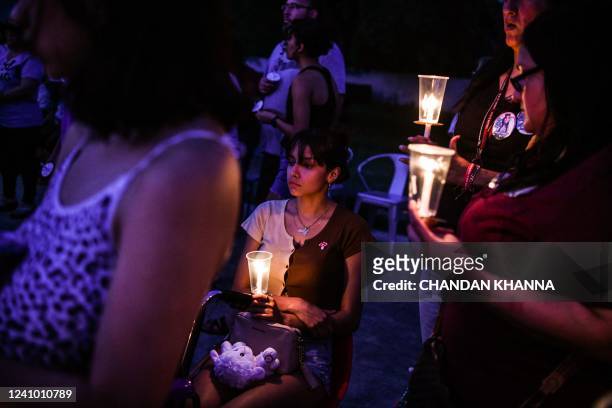 Young woman holds a candle during a candlelight vigil to honor and remember the victims of the mass shooting in Uvalde, Texas on May 30, 2022. -...