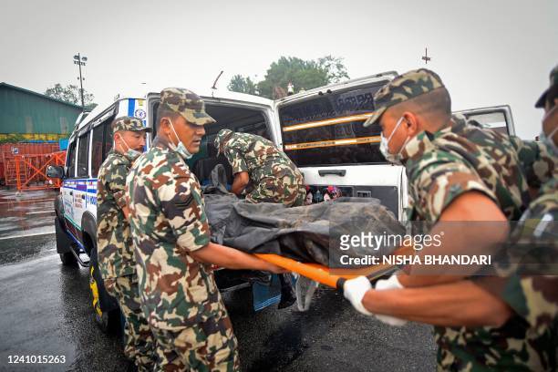 Members of Nepals security personnel carry the body of a victim of Twin Otter aircraft, operated by Tara Air that crashed earlier in the Himalayas,...
