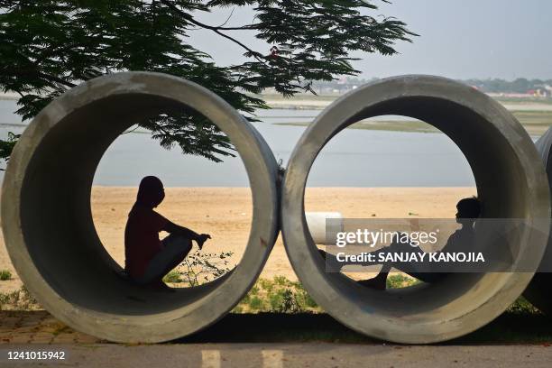 People rest inside cement pipes lying along the roadside on a hot summer day in Allahabad on May 31, 2022.