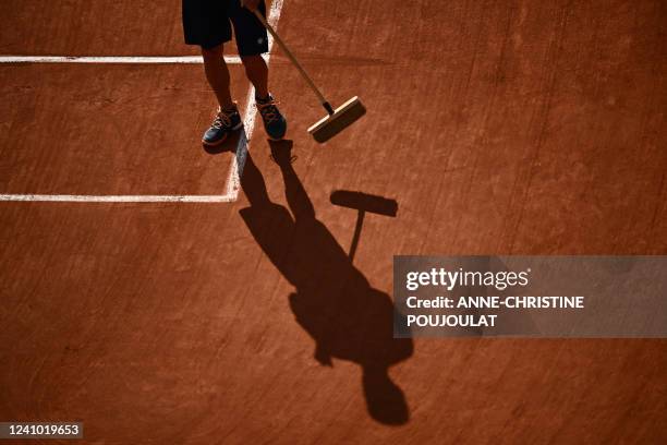 Worker sweeps the clay on the pitch during the men's quarter-final singles match between Spain's Carlos Alcaraz and Germany's Alexander Zverev on day...