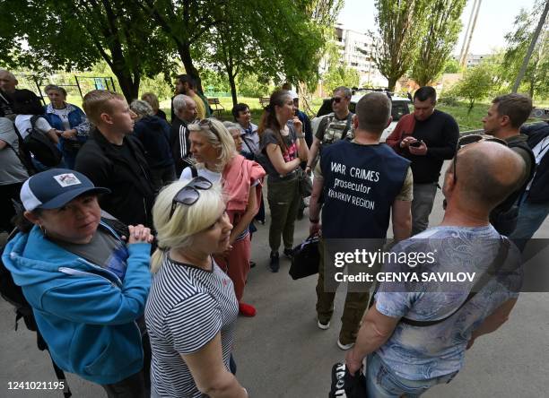 People talk to team members of the prosecutor of Kharkiv while they investigate on possible war crimes in the Saltivka district, northern Kharkiv, on...