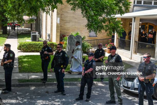 Priest walks out of the church as police stand guard in front of the hearse for Amerie Jo Garza, who died in the mass shooting at Robb Elementary...