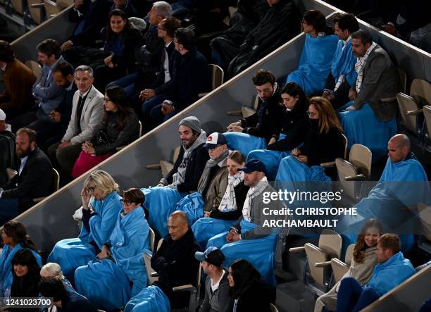 Supporters wear blankets as they are watching the men's singles match between Spain's Rafael Nadal and Serbia's Novak Djokovic on day ten of the...