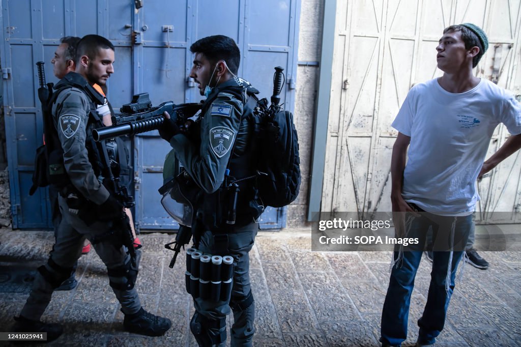 Border Police soldier faces Palestinians holding his weapon...