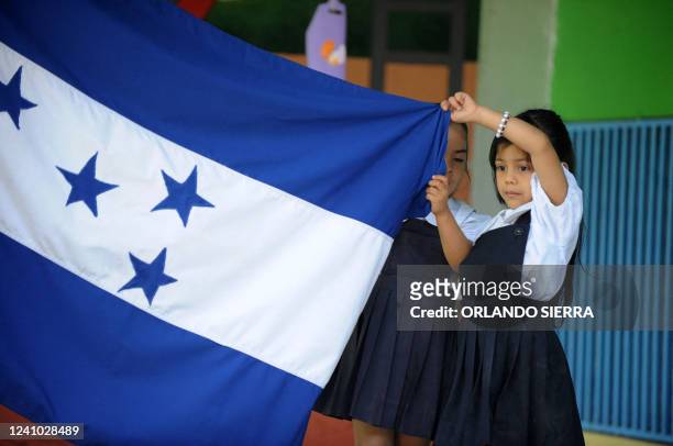 Two girls hold the Honduran national flag on the first day of classes in Honduras, at a school in Tegucigalpa on February 8, 2010. AFP PHOTO/Orlando...